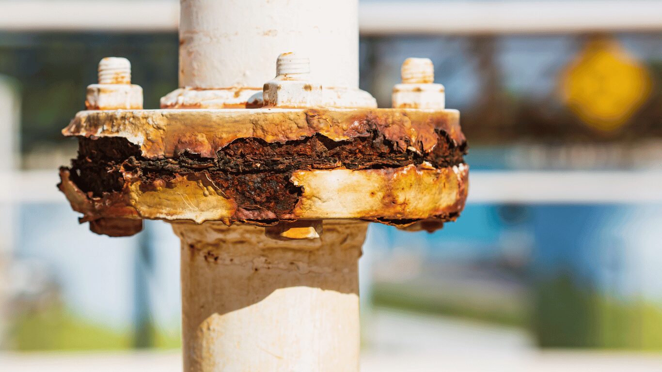 This close-up image shows an industrial pipe flange with extensive inhibitor corrosion, where rust, oxidation, and metal degradation have accumulated around the bolted connection. The visible corrosion buildup indicates the effects of prolonged exposure to moisture, harsh chemicals, or insufficient corrosion inhibitor treatment, which can weaken piping systems and increase the risk of leaks, equipment failure, and costly maintenance. The image highlights the importance of routine inspections, proper water treatment, and effective corrosion inhibitor programs to protect industrial infrastructure, improve system reliability, and extend equipment lifespan.