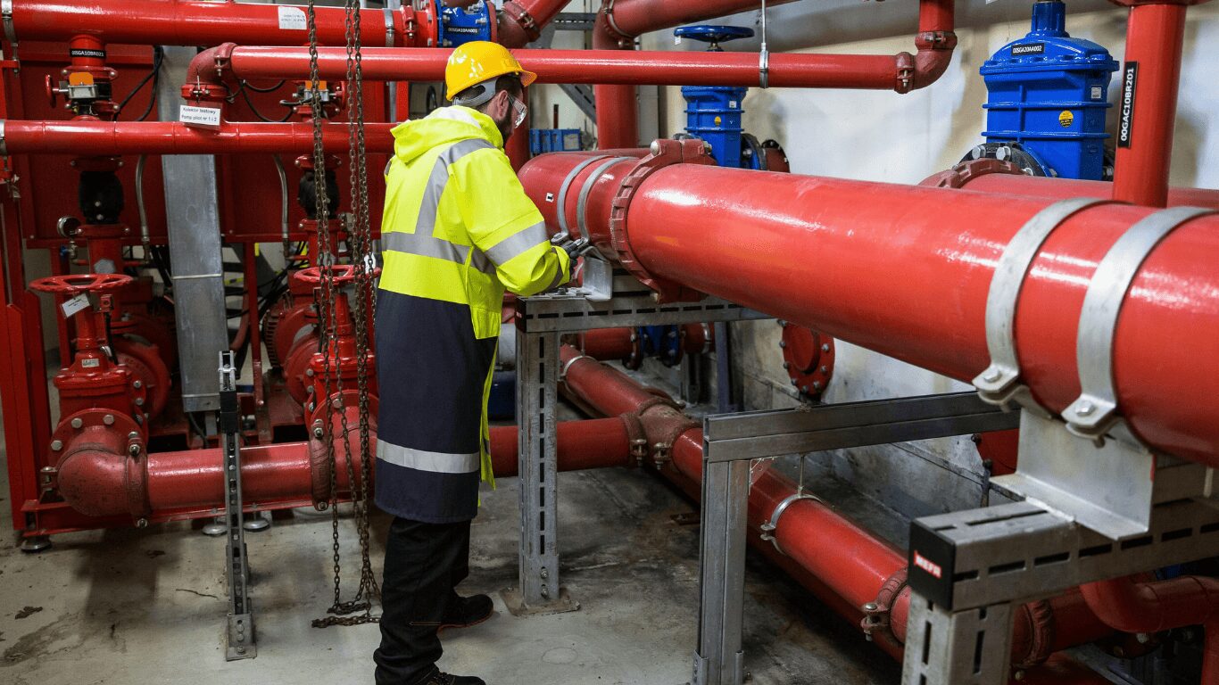 A building maintenance worker performing the pipe flushing process on a plumbing system to ensure clean water and high water quality. The flushing procedure helps remove construction debris, rust, scale, minerals, and contaminants from water pipes and pipelines, improving flow, pressure, and safety for property owners and building managers. The process follows American Water Works Association guidelines for chemical flushing, oil flushing, and routine maintenance to prevent leaks, corrosion, and flooding in water systems. Proper monitoring, equipment inspection, and filter replacement maintain clean pipes, prevent blockages, and support ice makers, faucets, aerators, and fixtures for whole house and facility plumbing. Maintaining temperature, velocity, and fluid control ensures feasible operation, reduces contamination, and protects health while keeping plumbing lines and components in top condition for cooking, drinking, and other uses.