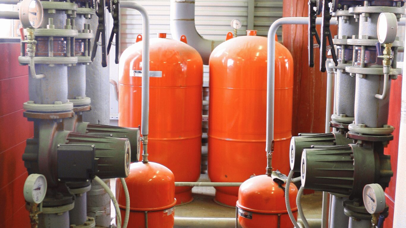 Industrial process water and industrial water treatment systems inside an industrial facility, showing pumps and tanks used for industrial water treatment, reverse osmosis, and membrane filtration to treating water, improve water quality, and remove contaminants like suspended solids, dissolved solids, dissolved gases, and heavy metals from raw water and industrial wastewater, supporting cooling water, tower water, and manufacturing processes in industries such as the food and beverage industry and data centers while improving operational efficiency, energy efficiency, and product quality.