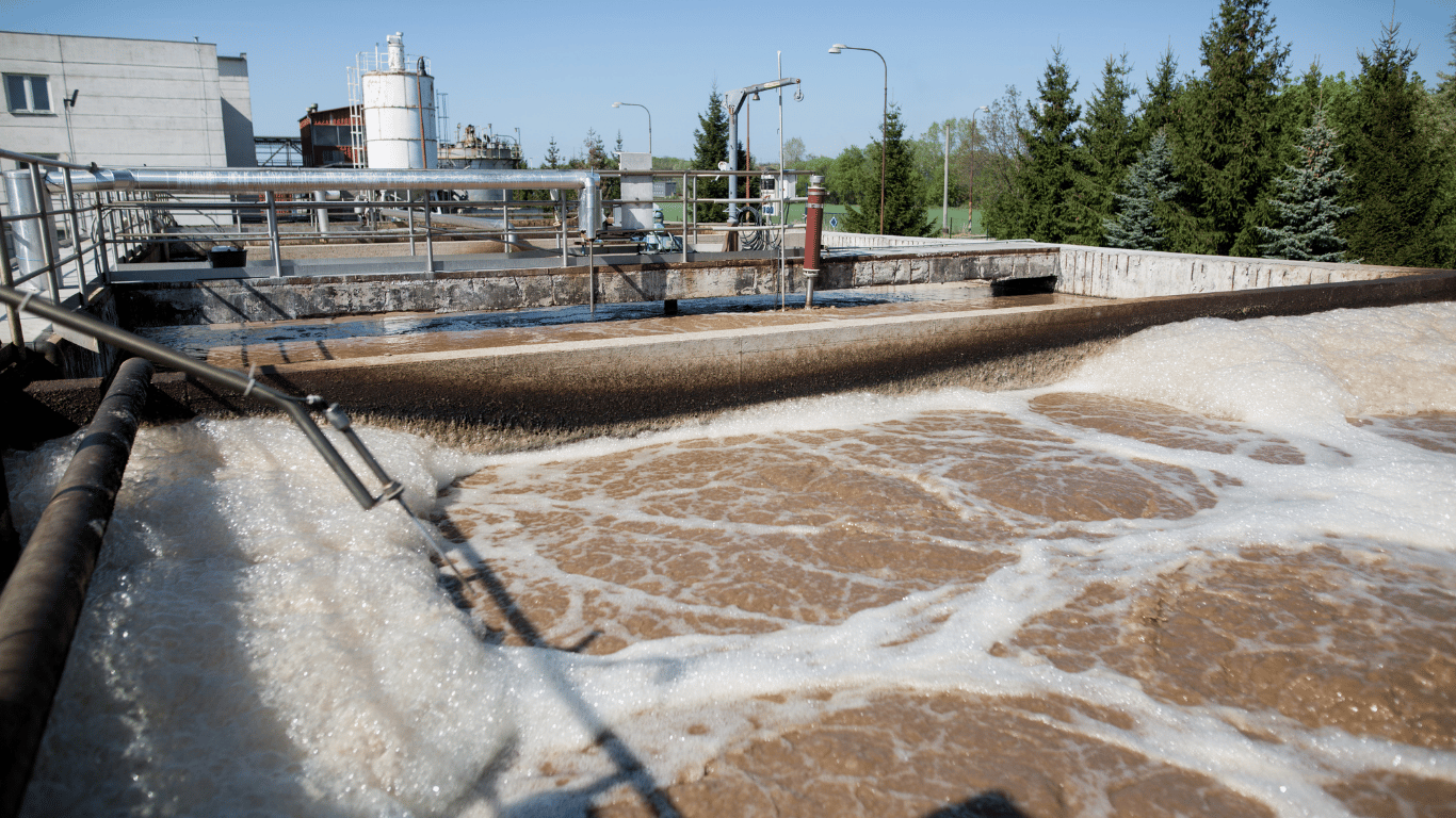 Wastewater treatment facility with active treatment tanks, airflow, and equipment for managing odorous air and odor pollution.
