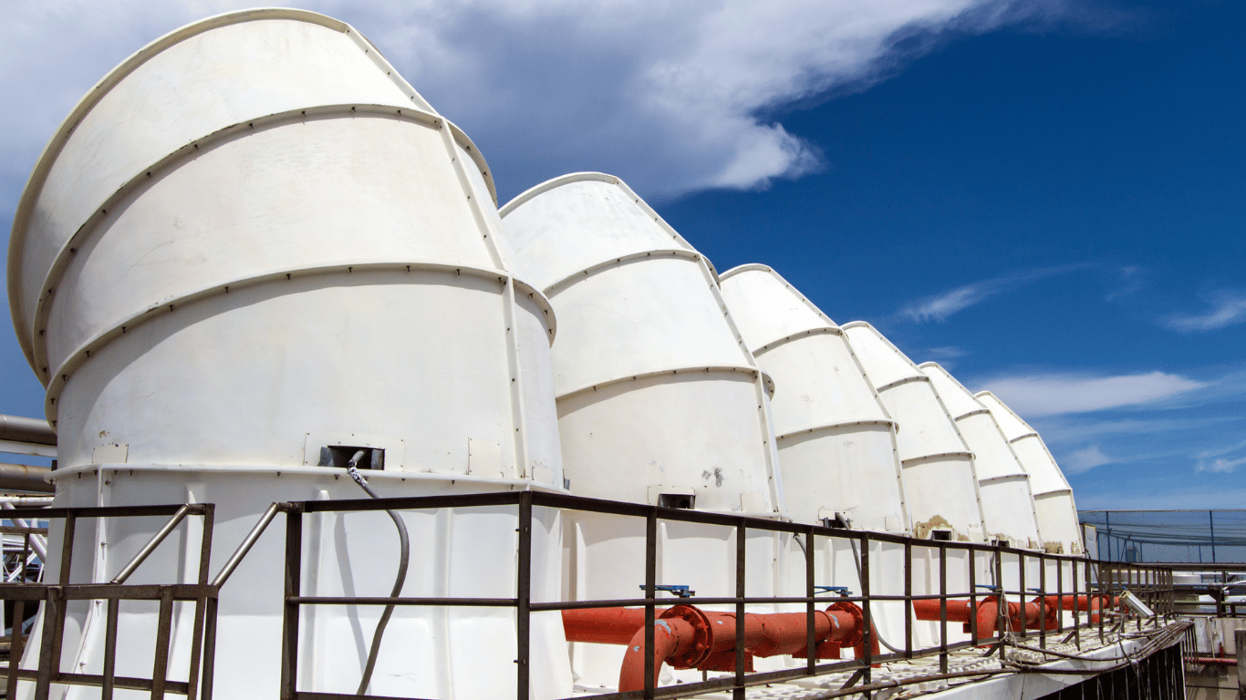 Industrial cooling towers with connected piping at a commercial facility, illustrating cooling tower water treatment and tower maintenance.